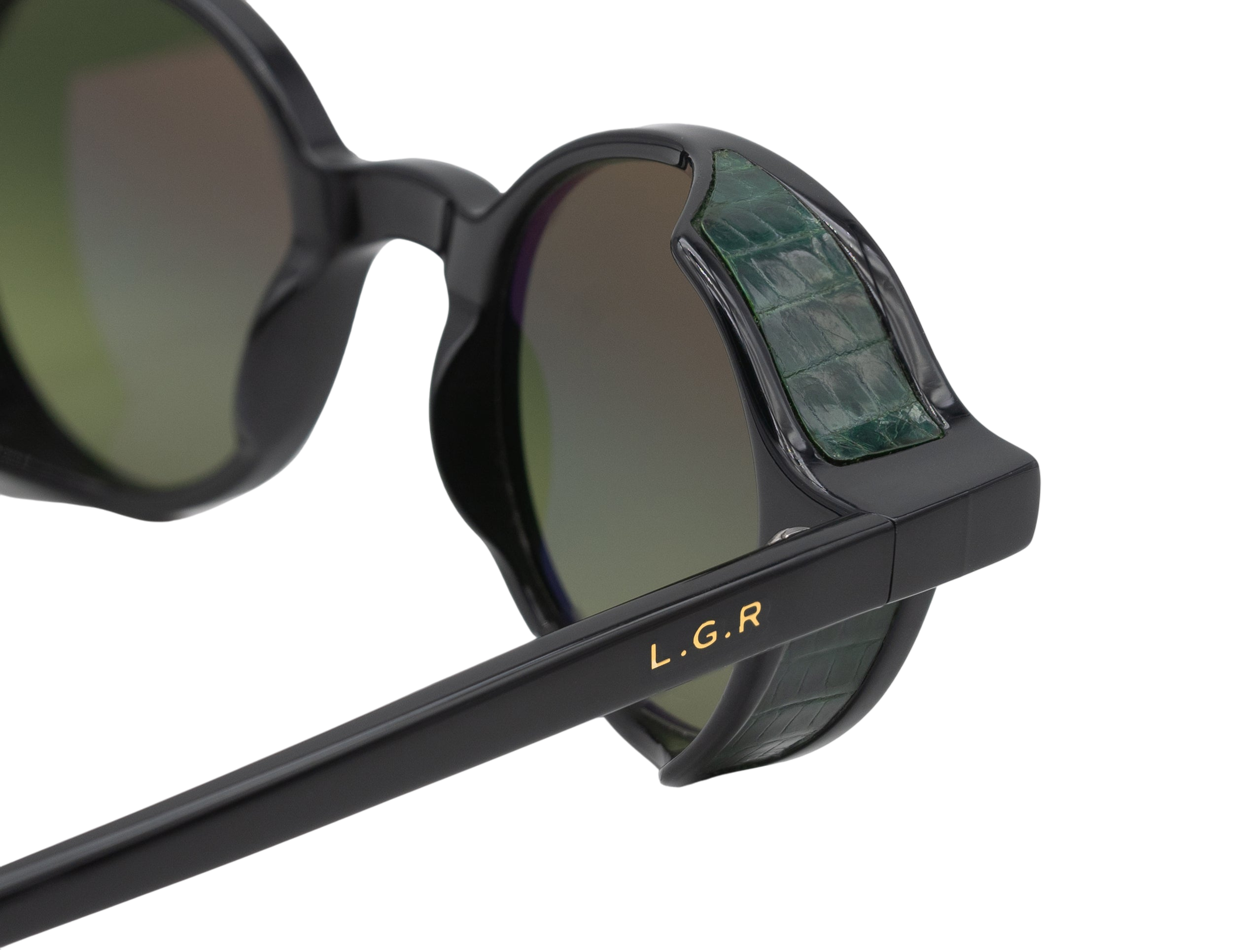 Close-up of black L.G.R. Reunion sunglasses with green crocodile textured side shields and gold logo
