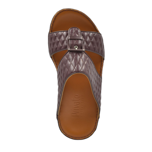 Top view of brown quilted leather luxury slip-on footwear with buckle detail and cushioned sole