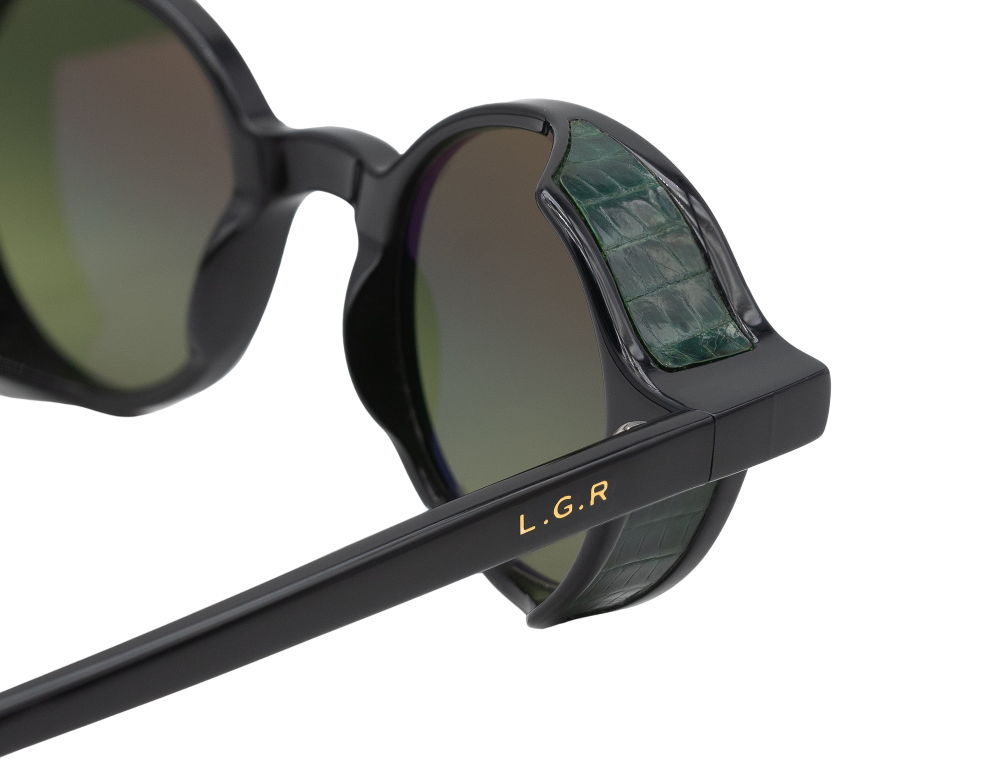 Close-up of black L.G.R. Reunion sunglasses with green crocodile textured side shields and gold logo