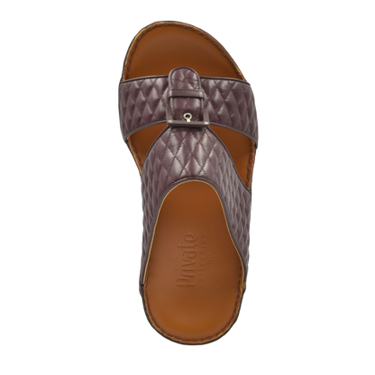 Top view of brown quilted leather luxury slip-on footwear with buckle detail and cushioned sole