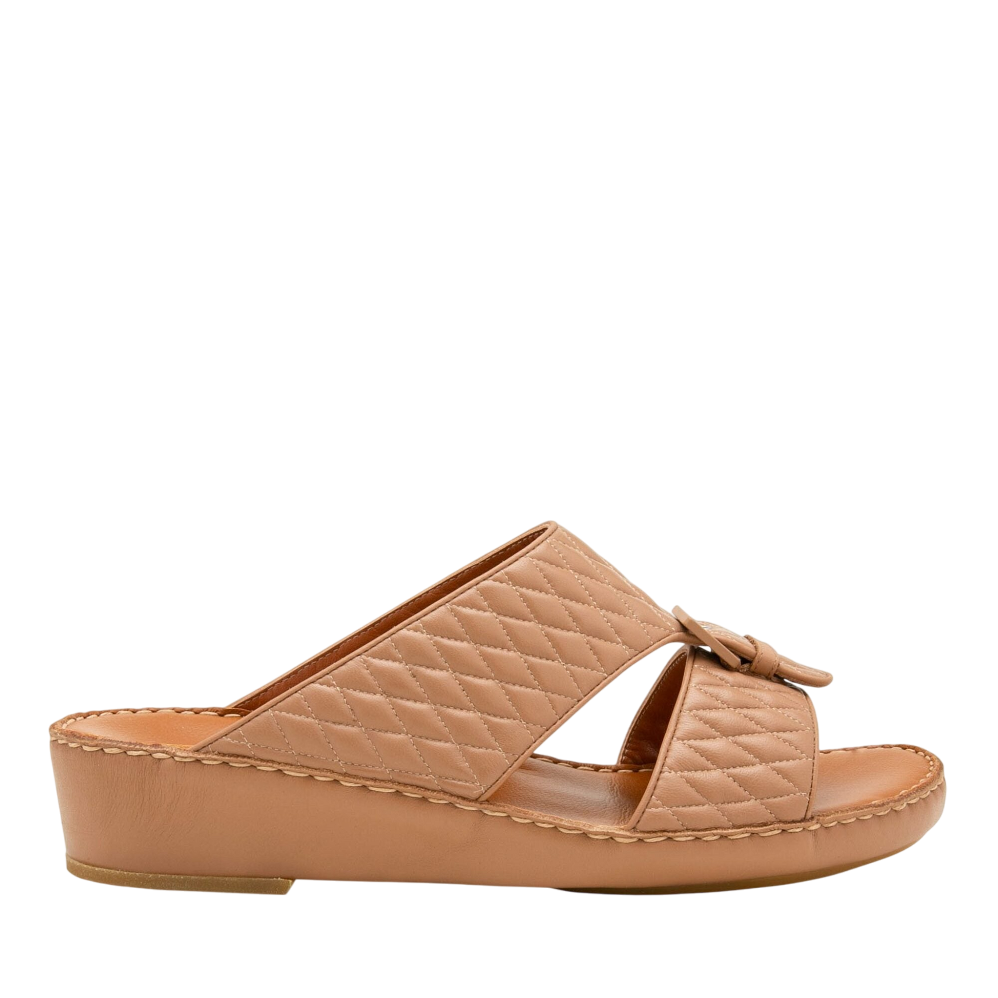 Tan quilted luxury slip-on footwear with low wedge heel and bow detail for stylish comfort