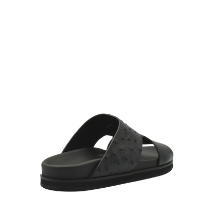 Black slide sandal featuring ostrich leather footwear with textured upper and cushioned sole