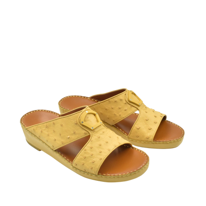 Yellow ostrich leather sandals with open toe and buckle detail on a white background